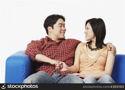 Close-up of a young couple sitting on a couch looking at each other