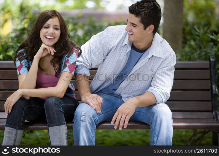 Close-up of a young couple sitting on a park bench and smiling