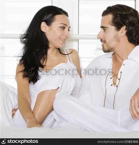 Close-up of a young couple sitting on the bed and looking at each other