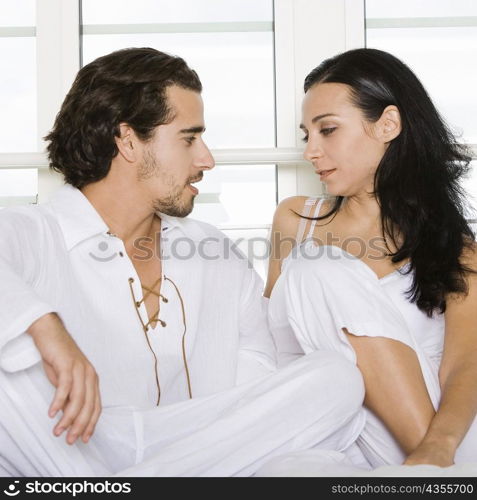 Close-up of a young couple sitting on the bed and looking at each other