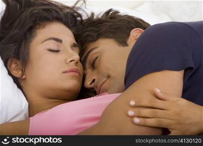 Close-up of a young couple sleeping on a bed