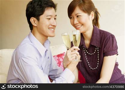 Close-up of a young couple smiling and toasting champagne flutes