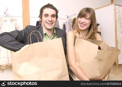 Close-up of a young couple standing in a clothing store and carrying shopping bags