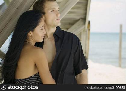 Close-up of a young couple standing on the beach and looking away