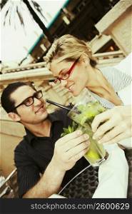 Close-up of a young couple toasting with mojito drinks