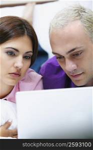 Close-up of a young couple using a laptop on the bed