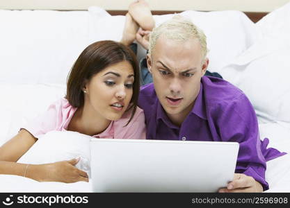 Close-up of a young couple using a laptop on the bed