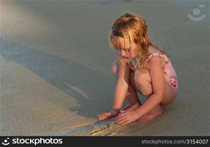 Close-up of a young girl (6-8) playing with sand on a beach, Moorea, Tahiti, French Polynesia, South Pacific
