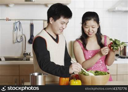 Close-up of a young man and a mid adult woman preparing food