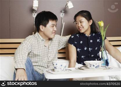 Close-up of a young man and a mid adult woman sitting on the bed