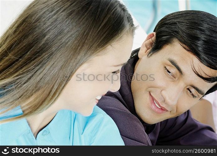Close-up of a young man and a teenage girl looking at each other and smiling