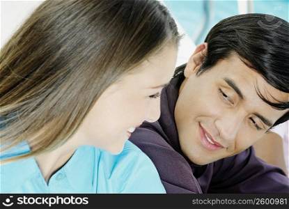 Close-up of a young man and a teenage girl looking at each other and smiling