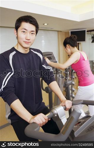 Close-up of a young man and a young woman exercising in a gym