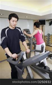 Close-up of a young man and a young woman exercising in a gym