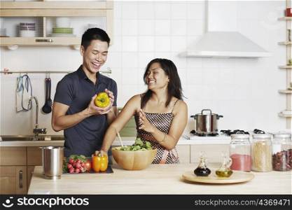 Close-up of a young man and a young woman standing and holding yellow bell peppers