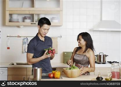 Close-up of a young man and a young woman standing and holding root vegetables