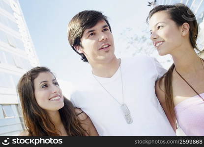 Close-up of a young man and two young women smiling