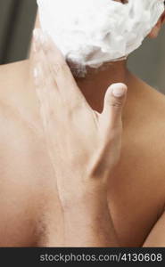 Close-up of a young man applying shaving cream on his face