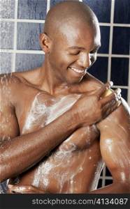 Close-up of a young man applying soap on his body