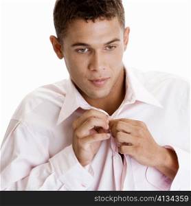 Close-up of a young man buttoning his shirt
