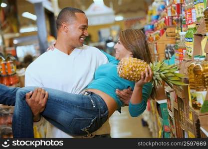 Close-up of a young man carrying a young woman in a supermarket