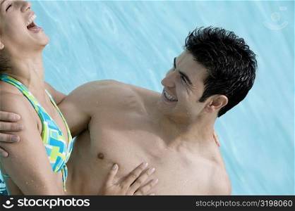 Close-up of a young man carrying a young woman in his arms in a swimming pool