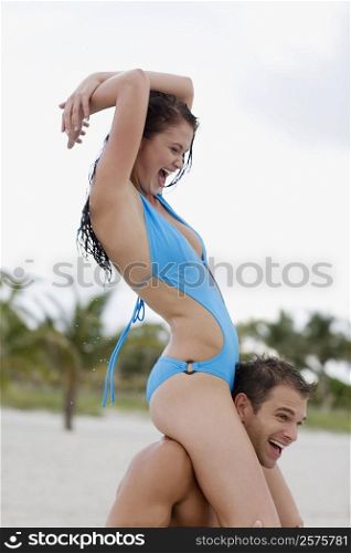 Close-up of a young man carrying a young woman on his shoulders and laughing