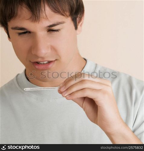 Close-up of a young man checking the temperature on a thermometer