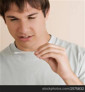 Close-up of a young man checking the temperature on a thermometer