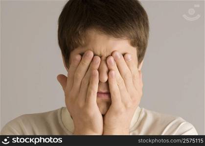 Close-up of a young man covering his eyes with his hands