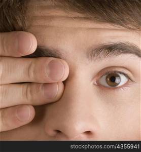 Close-up of a young man covering his one eye