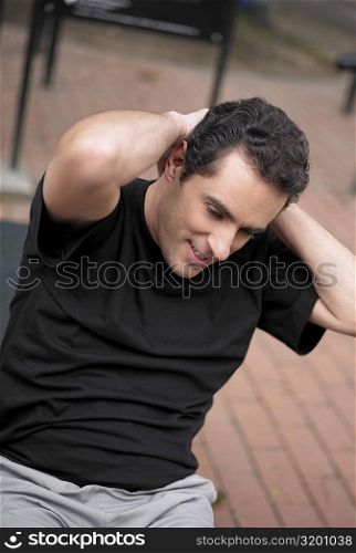 Close-up of a young man doing sit-ups with his hands behind his head