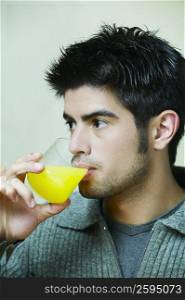 Close-up of a young man drinking a glass of orange juice