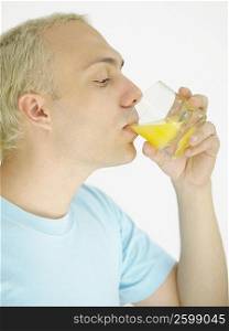 Close-up of a young man drinking orange juice from a glass