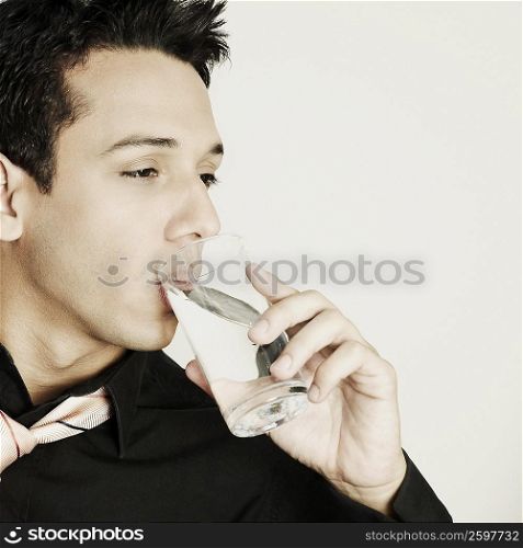 Close-up of a young man drinking water from a glass