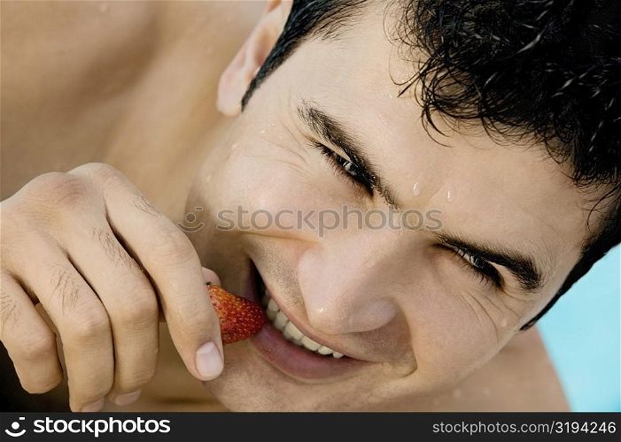 Close-up of a young man eating a strawberry