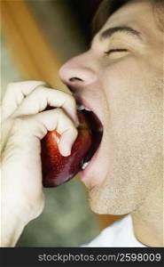 Close-up of a young man eating an apple