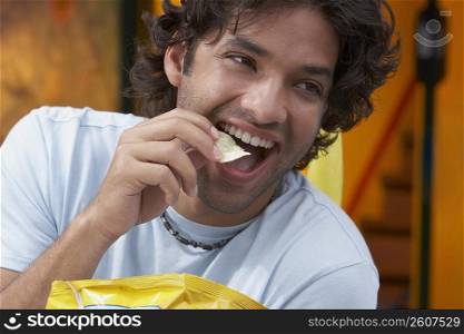 Close-up of a young man eating potato chips