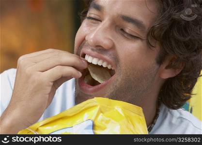 Close-up of a young man eating potato chips