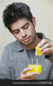 Close-up of a young man extracting juice from an orange