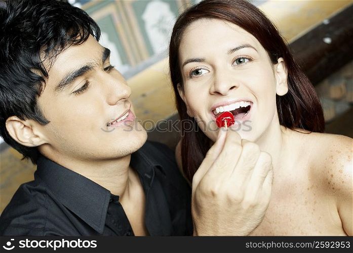 Close-up of a young man feeding a cherry to a young woman