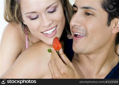 Close-up of a young man feeding a strawberry to a young woman