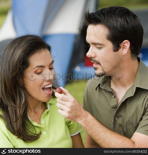 Close-up of a young man feeding a young woman a cherry