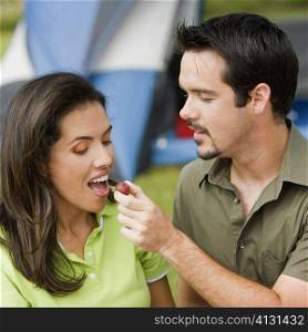 Close-up of a young man feeding a young woman a cherry