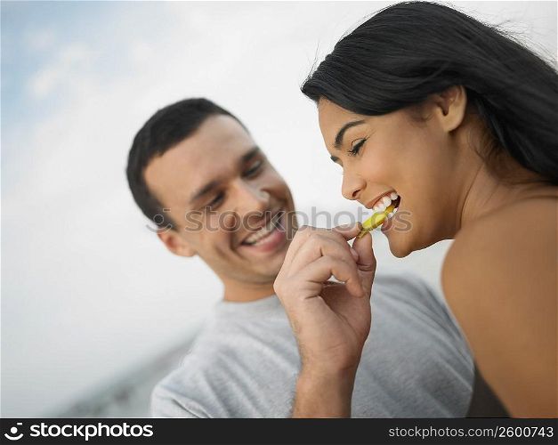 Close-up of a young man feeding a young woman a slice of fruit