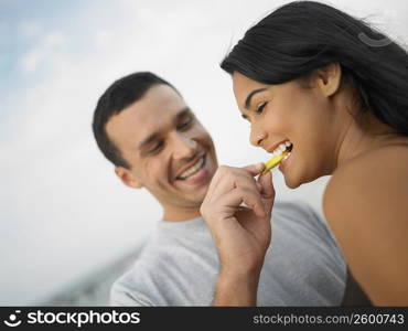 Close-up of a young man feeding a young woman a slice of fruit