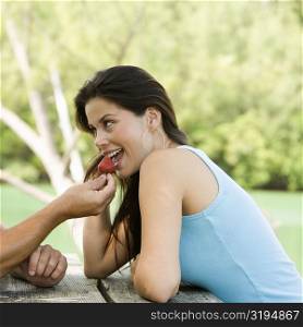 Close-up of a young man feeding a young woman a strawberry
