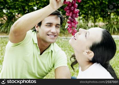Close-up of a young man feeding grapes to a young woman