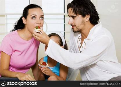 Close-up of a young man feeding pastry to a young woman