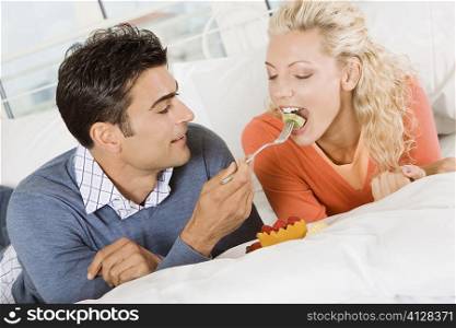 Close-up of a young man feeding salad to a young woman